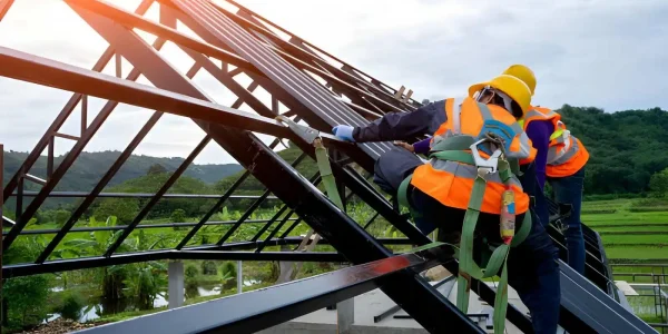assisting the Board of Directors in handling the day-to-day maintenance Two workers in safety harnesses and high-visibility vests installing steel roof framing on a building under construction